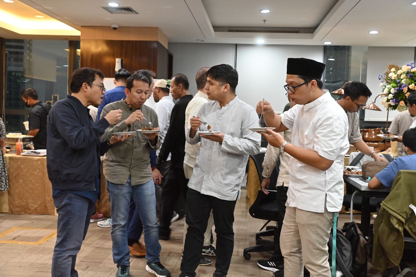 Colleagues chatting over plates of food at the office iftar